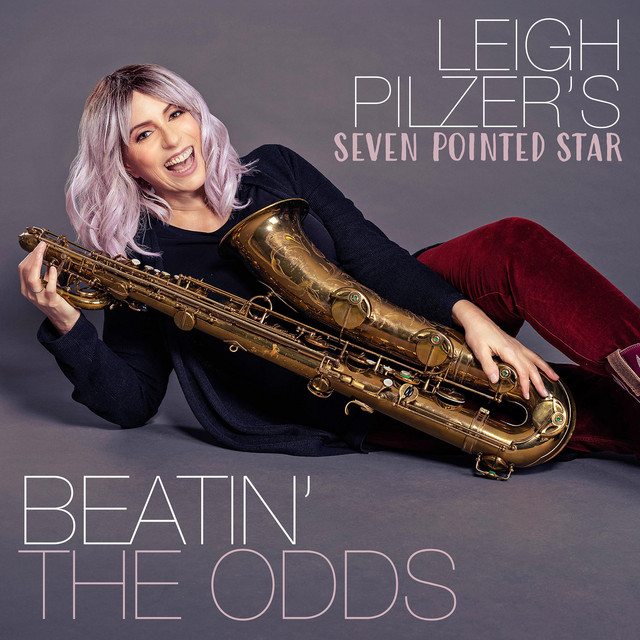 Beatin' The Odds album cover. Leigh Pilzer splayed out under the album title, sporting a saxophone and a smile.