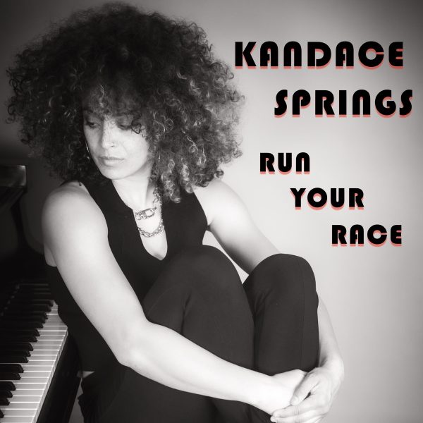 Run Your Race album cover. Kandace Springs centered in the frame in black and white looking at her piano beside her, with her name and album title displayed beside her.